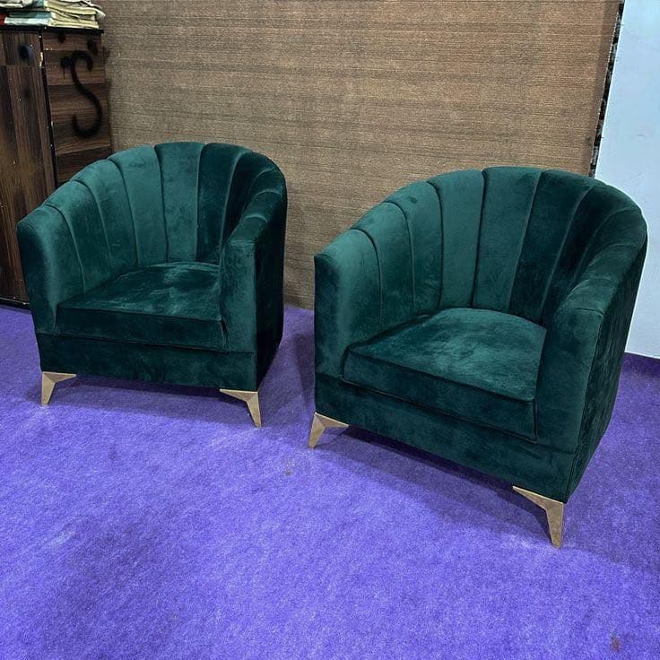 Pair of hunter green channel-tufted barrel chairs in the showroom