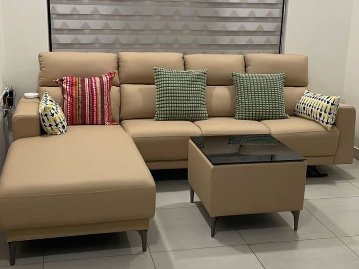 Camel-coloured L-shaped sectional sofa with patterned cushions in the showroom