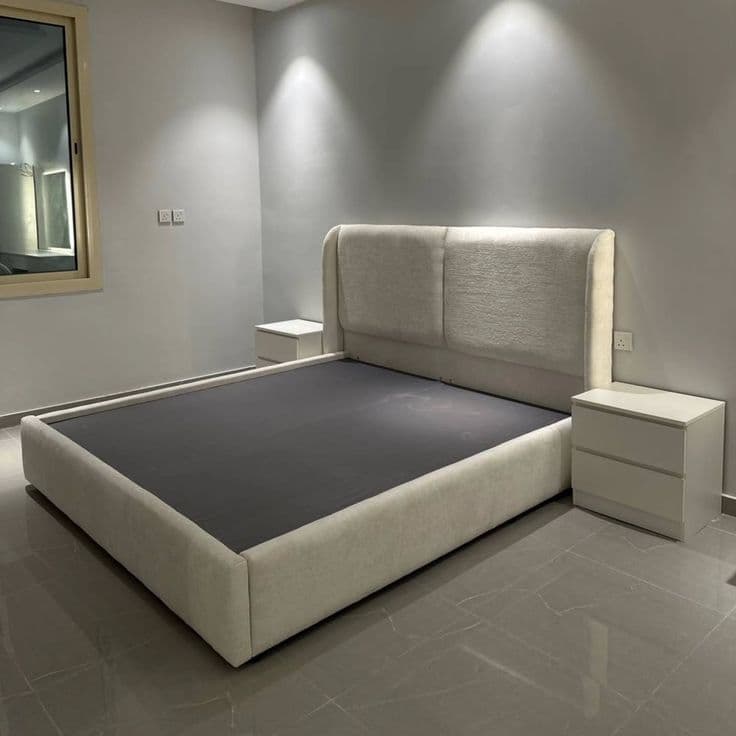 Grey upholstered bed with a wide headboard and matching nightstands