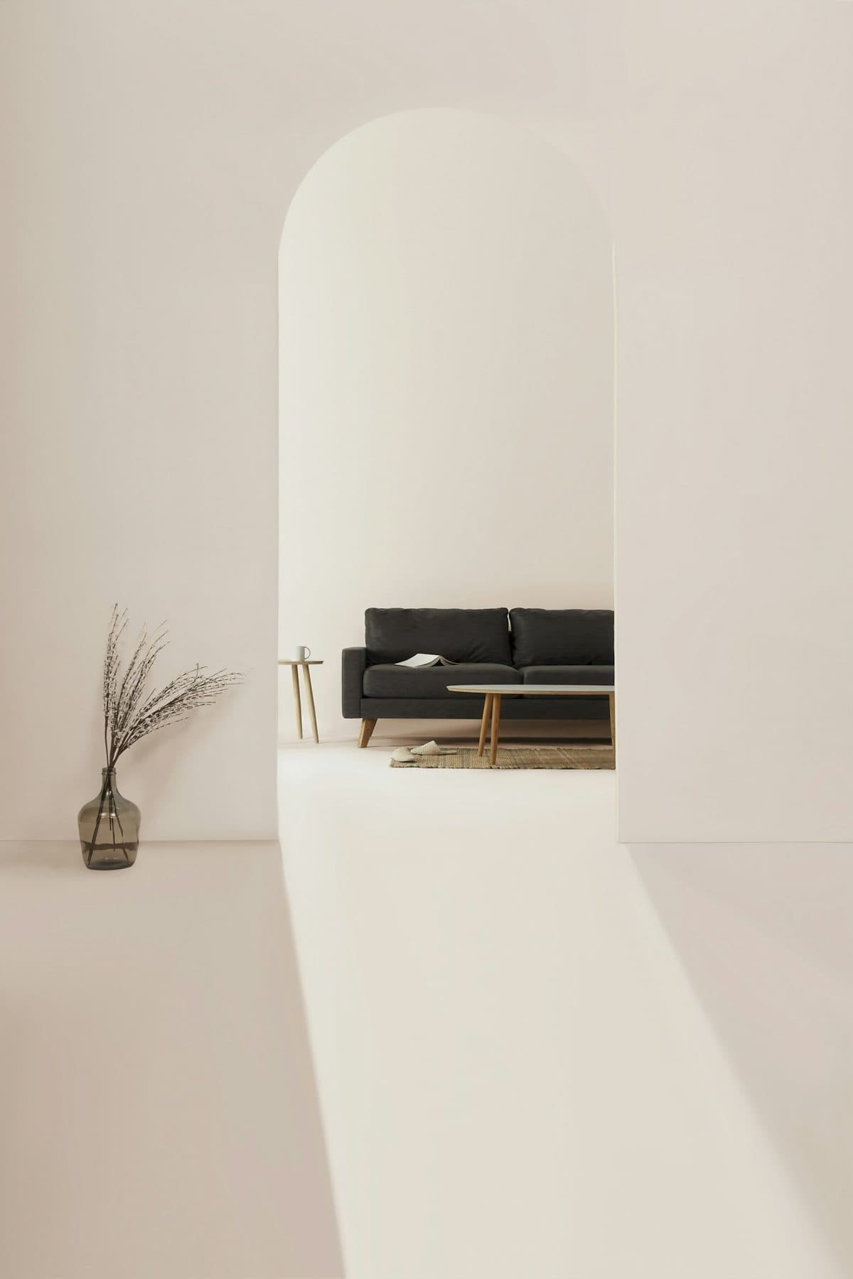 Charcoal two-seater sofa framed by an arched opening in a pale, minimal interior