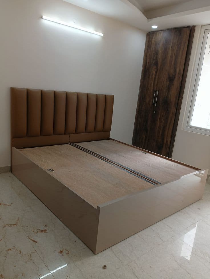 Tan channel-tufted bed installed in a bedroom beside a wood panelled door