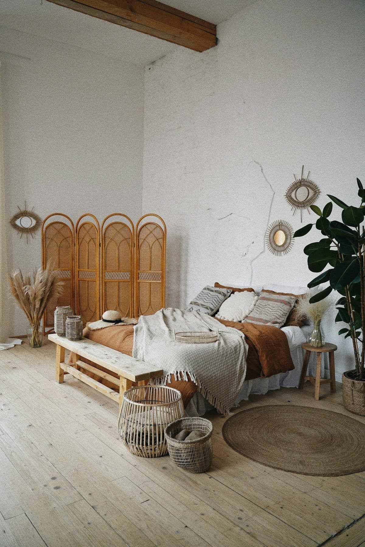 Bed with a woven cane and wood headboard in a light, textured bedroom