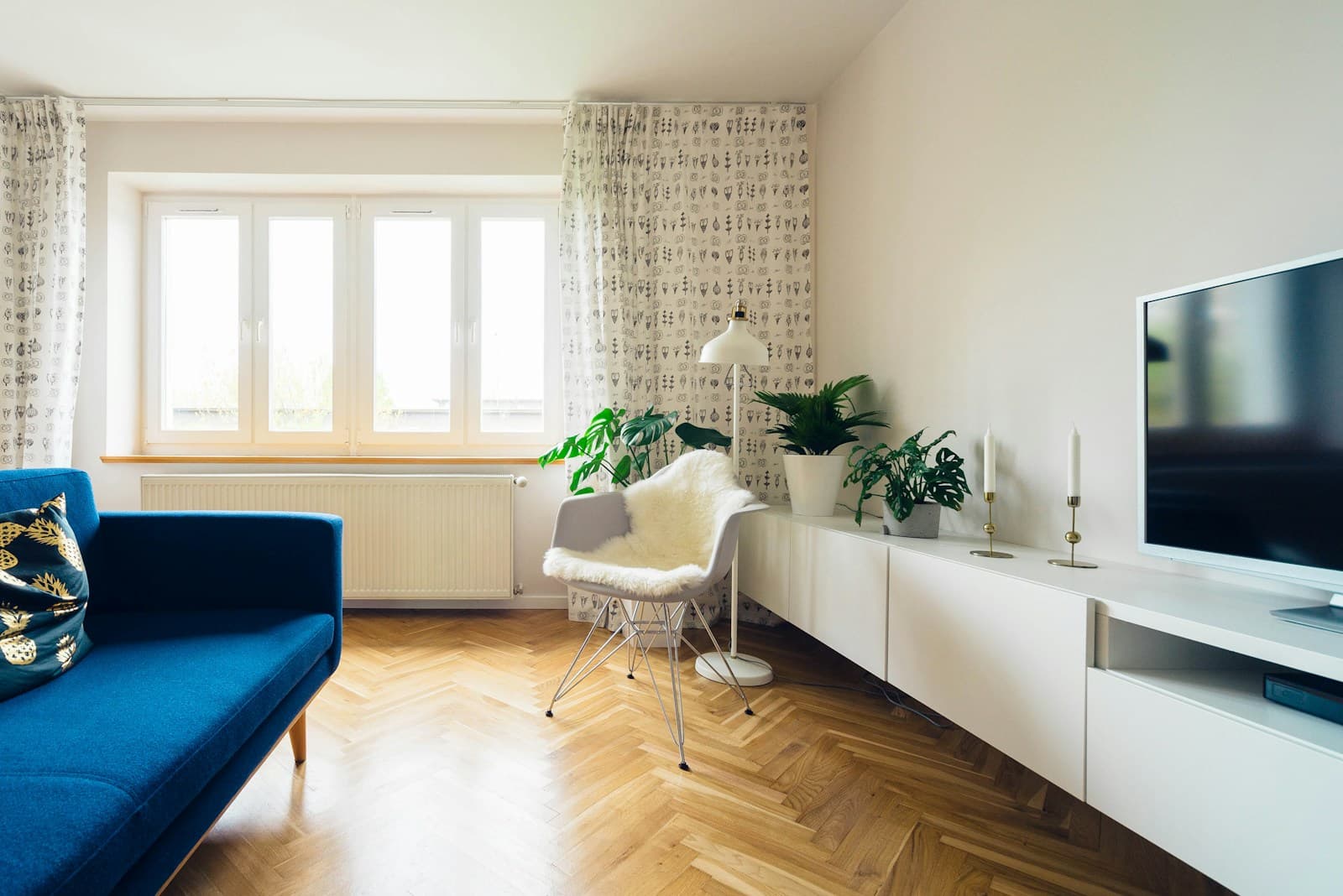Long white floor standing TV console unit on a herringbone wood floor