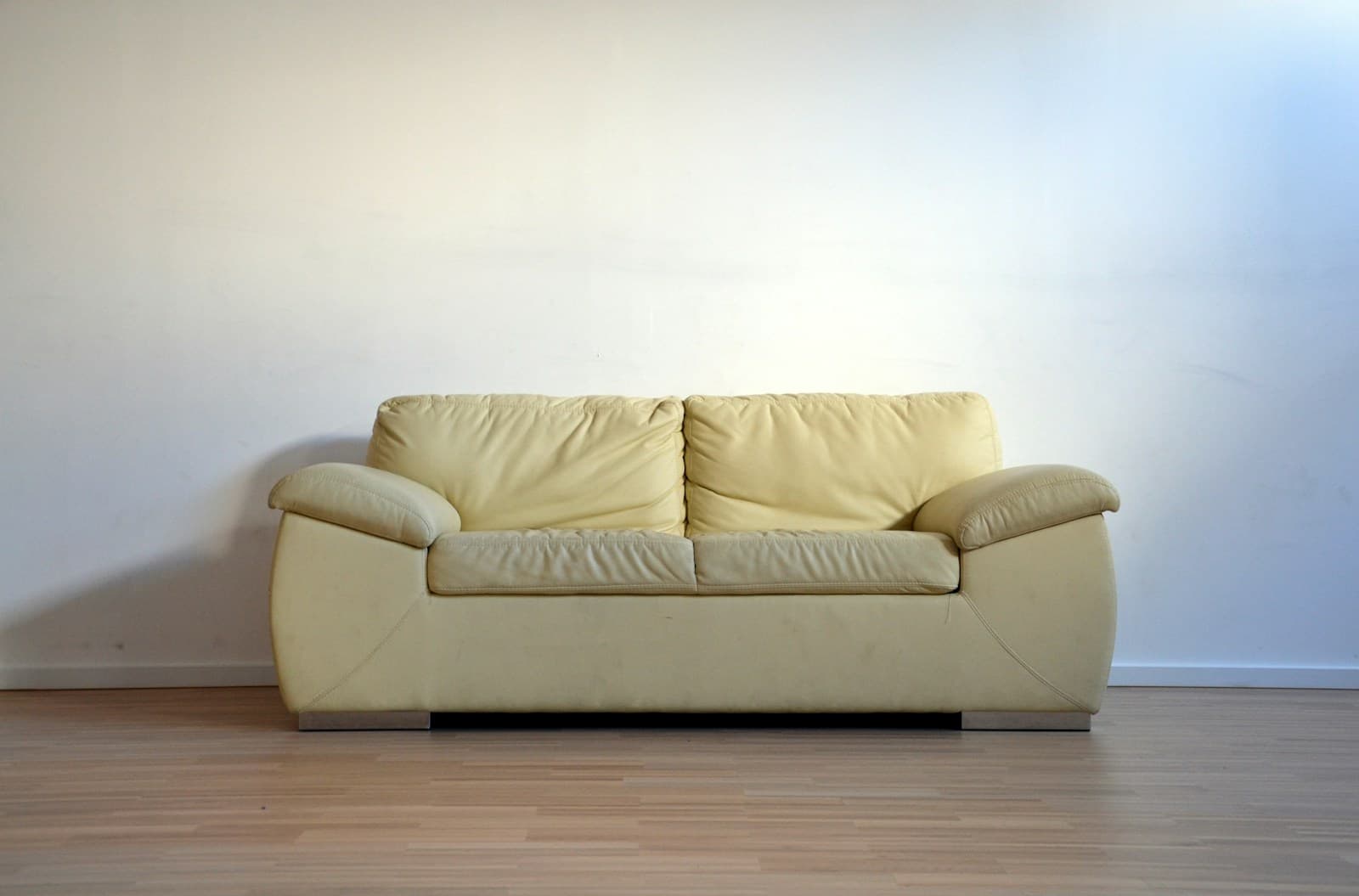 Cream leather two-seater loveseat against a plain wall