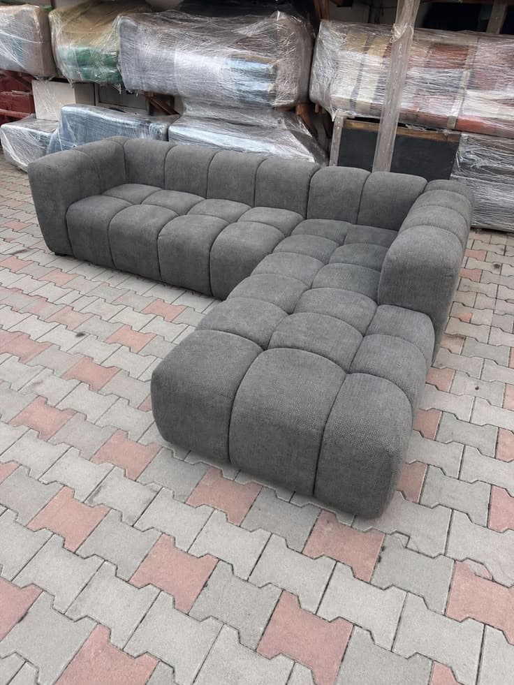 Charcoal grey modular channel-tufted sectional sofa, built from individual seat modules, fresh from the workshop