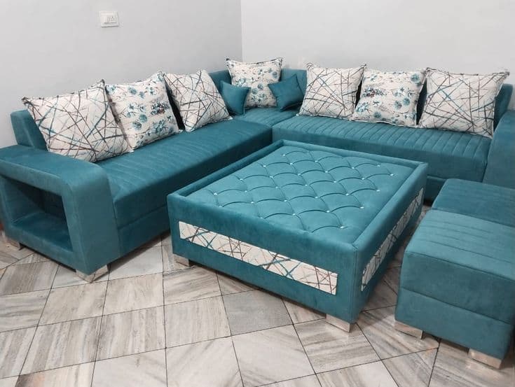 Teal channel-tufted L-shaped sofa with a matching ottoman and open-shelf armrest, in the showroom