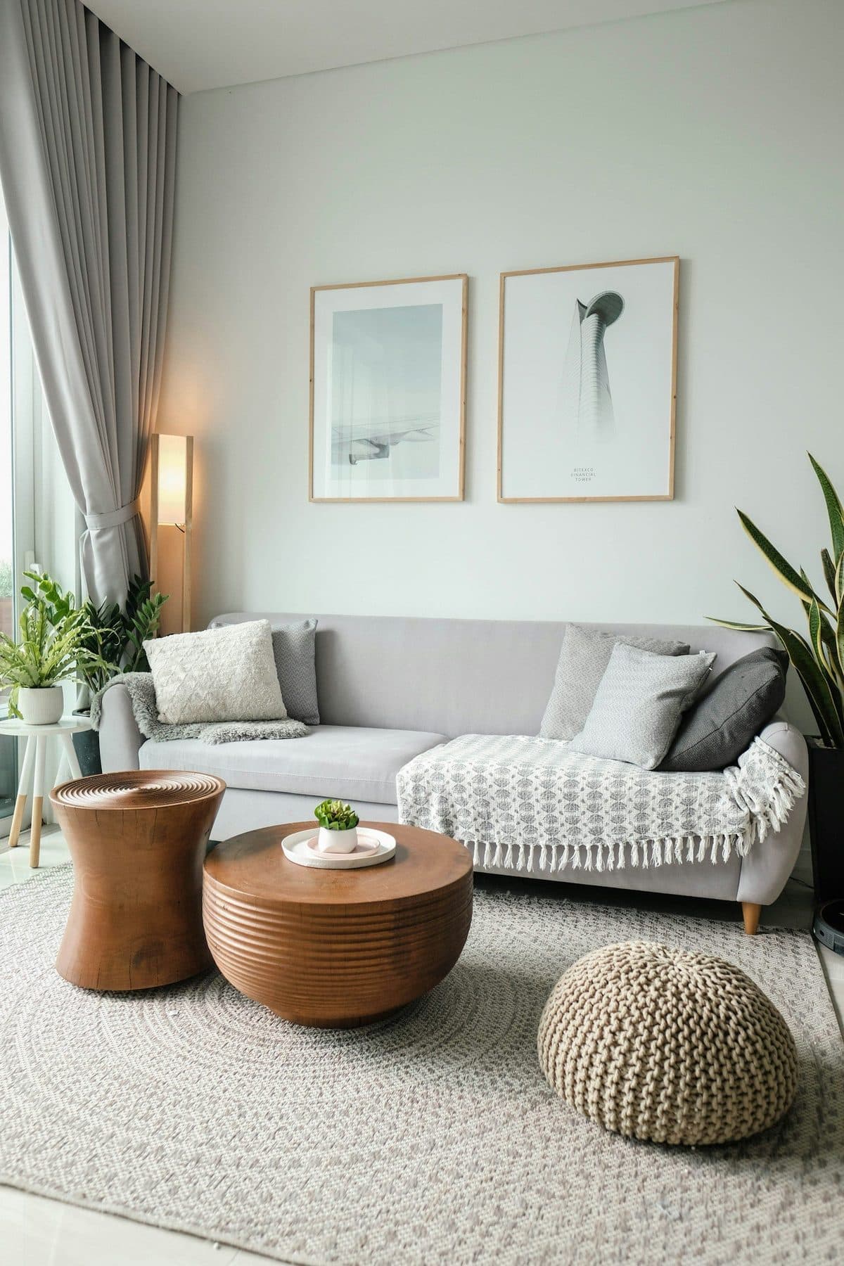 Compact living room with a grey sofa, round wooden centre table and a knitted pouf on a jute rug