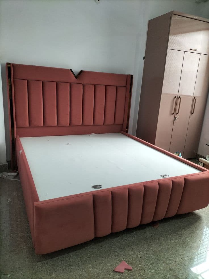 Coral upholstered bed with a panelled headboard installed beside a built-in wardrobe