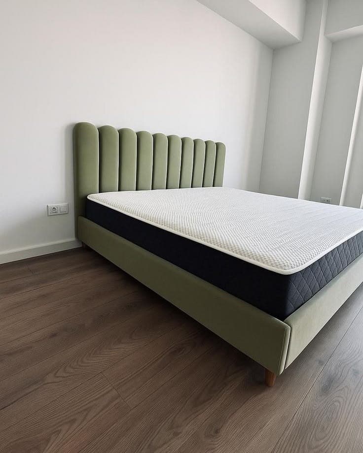 Sage green bed with a sunburst channel-tufted headboard in a bright bedroom