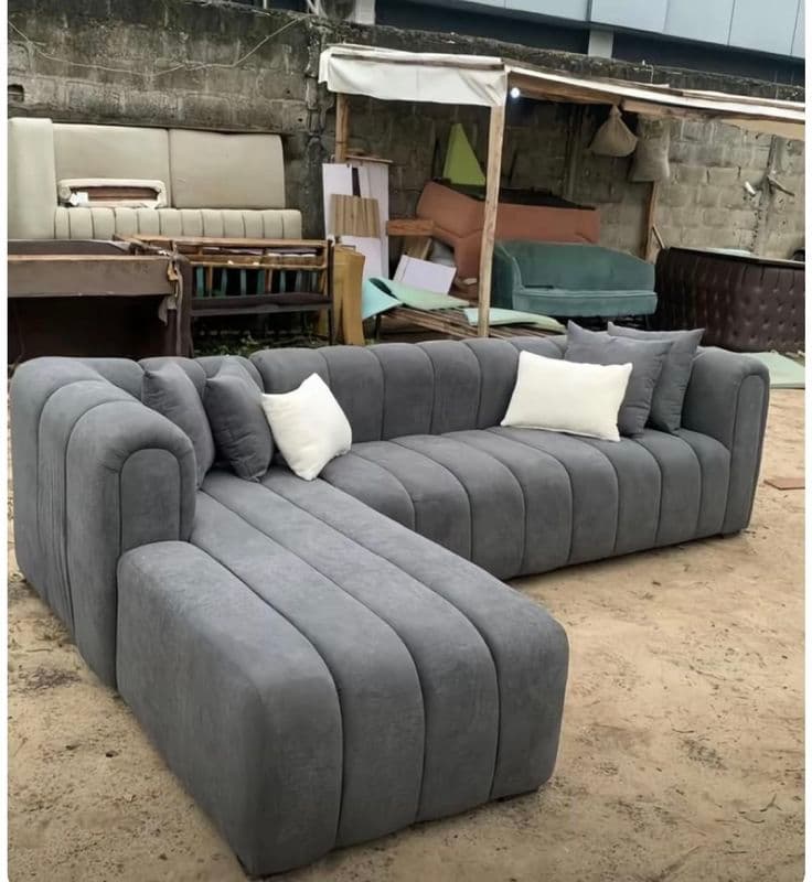 Charcoal grey modular channel-tufted L-shaped sectional sofa with a chaise, photographed in the yard